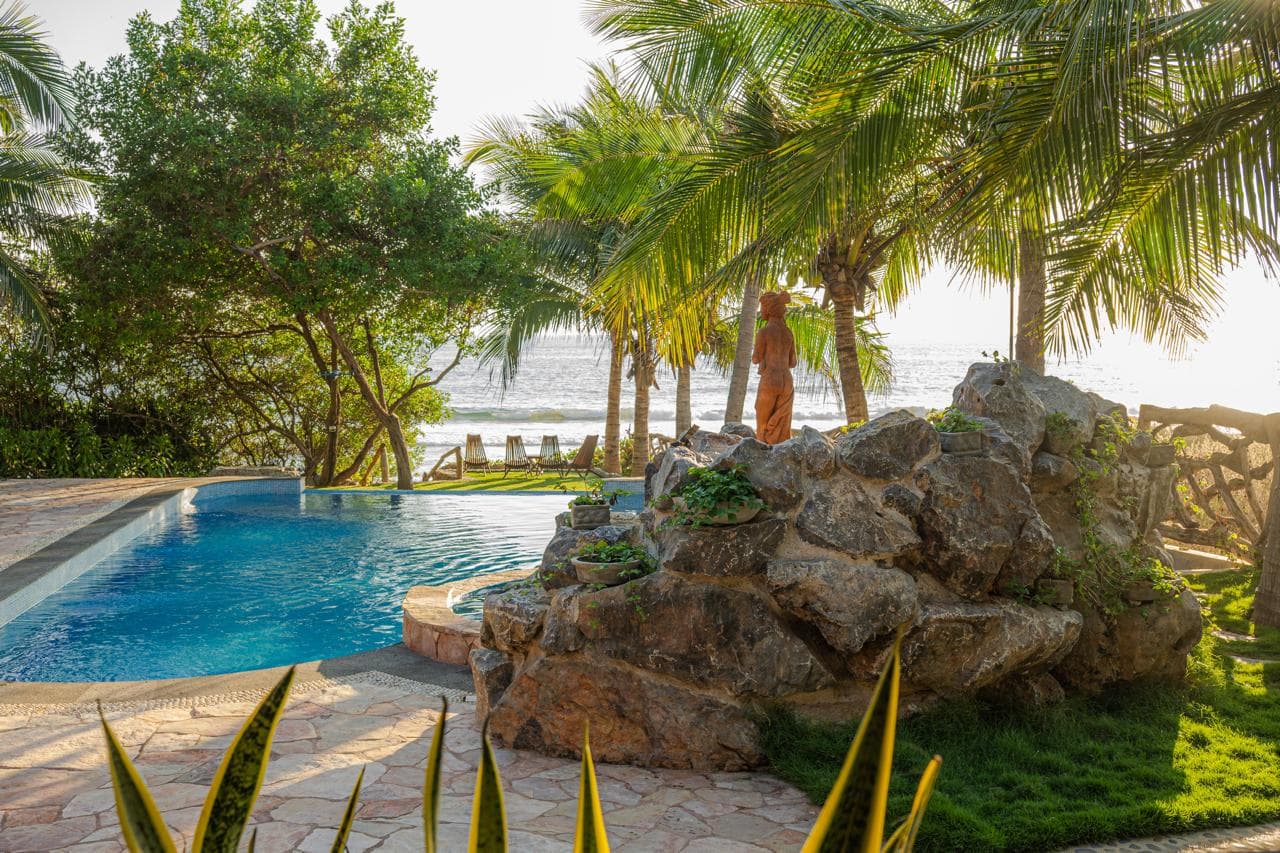 Piscine privée bordée de roche volcanique et de palmiers, avec vue sur le Pacifique à la Villa Las Palmas