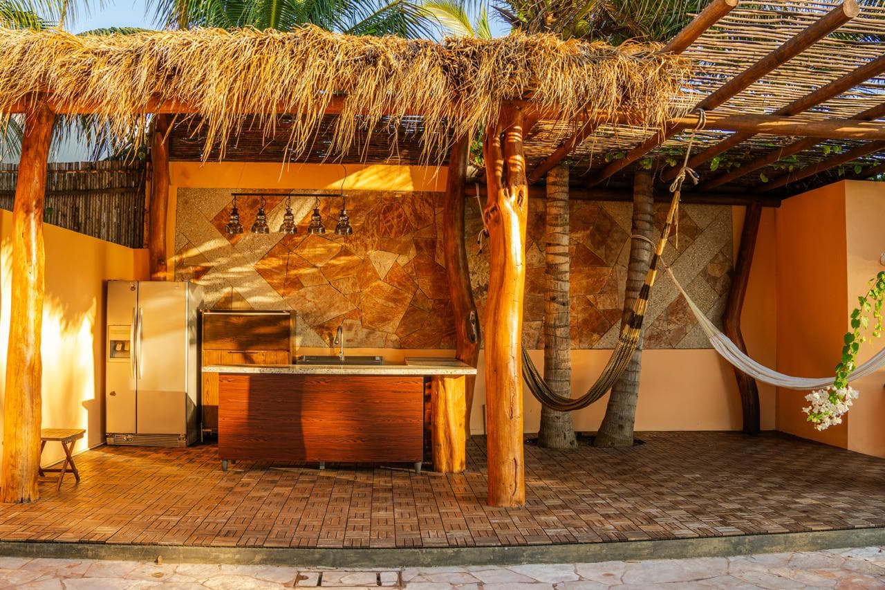 Bar extérieur sous une palapa, avec des hamacs suspendus entre les poteaux