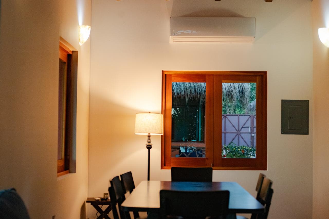 Salle à manger climatisée avec table pour six et fenêtre donnant sur le jardin